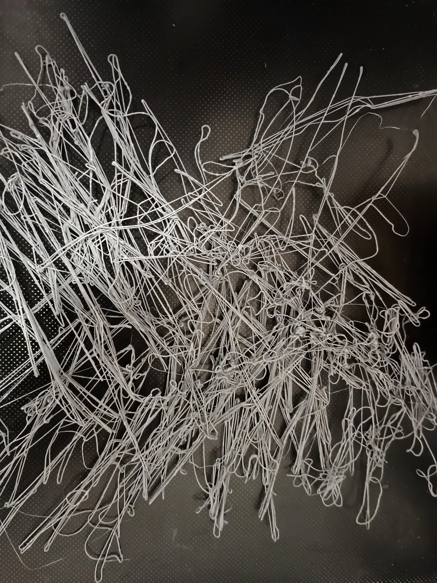 A failed 3D print resembling tangled spaghetti on the print bed